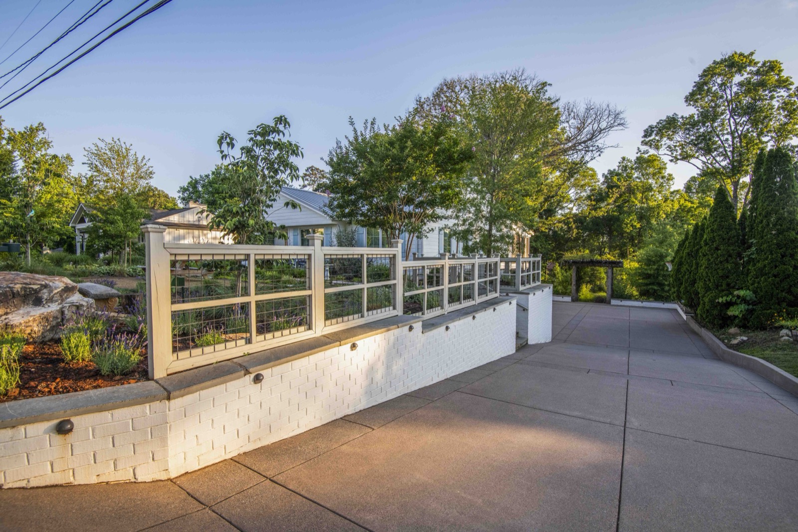 North Shore front yard after renovation — raised native garden behind a white retaining wall and concrete drive court