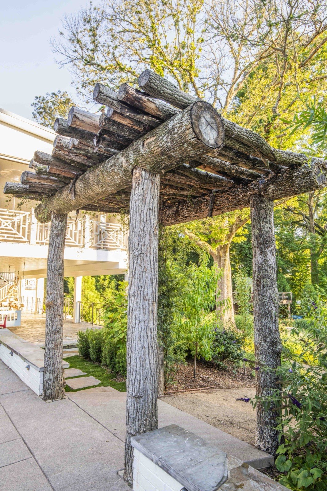 Hand-built arbor of reclaimed logs and timber framing a garden walkway