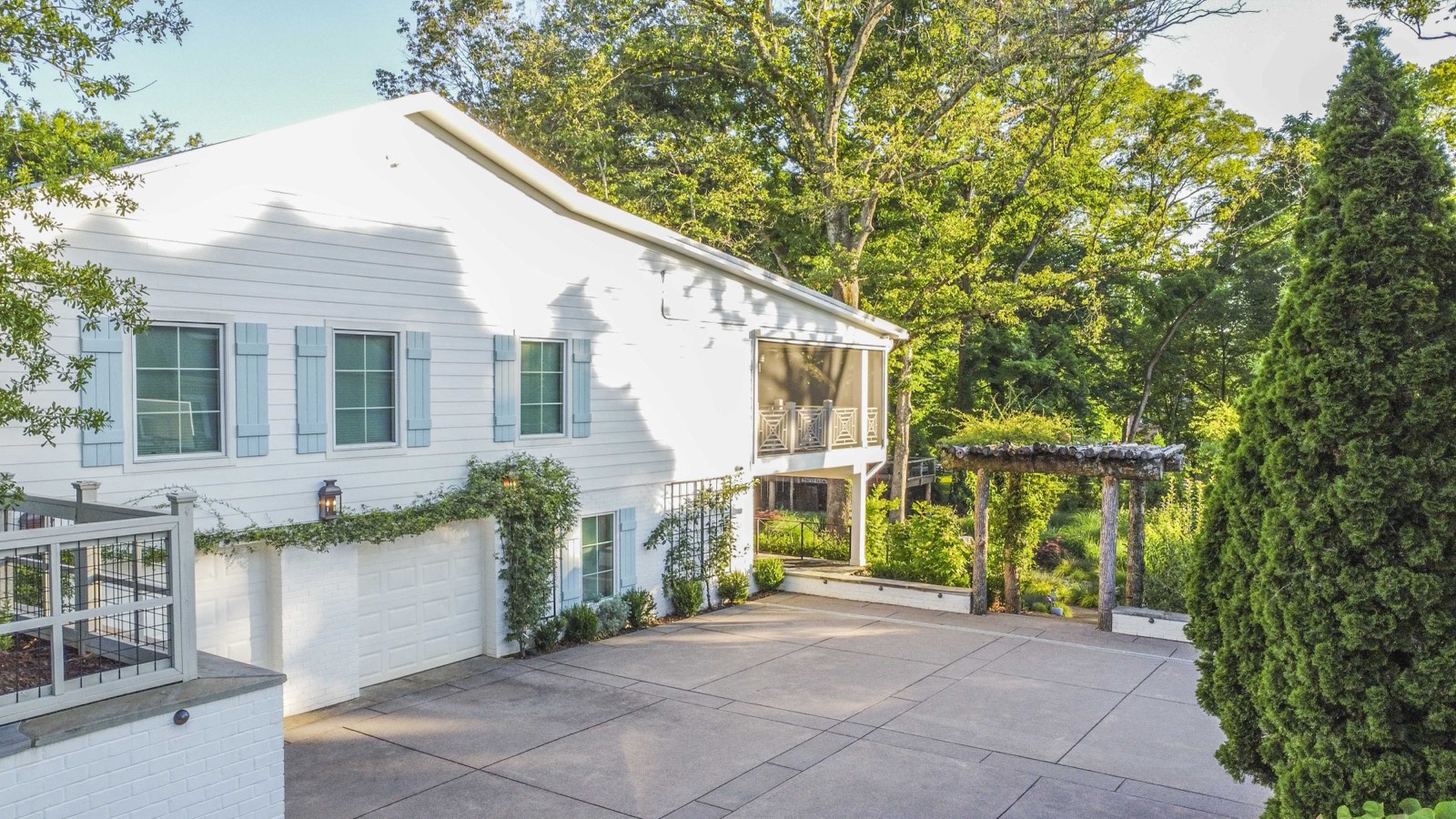 Aerial of the white home, standing-seam metal roof, and concrete drive court
