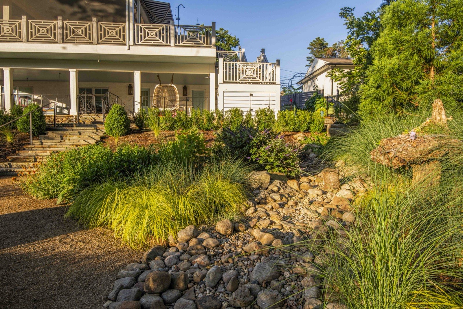 Dry-creek drainage feature edged with river rock and ornamental grasses