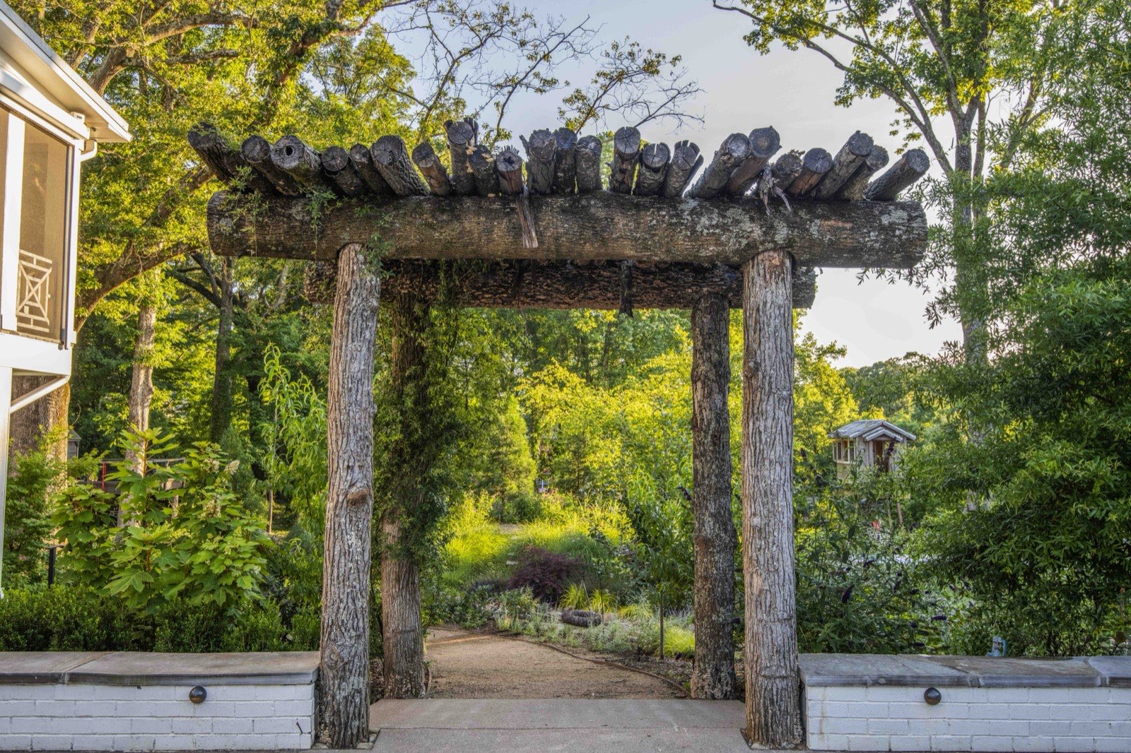 Rustic natural-timber gateway opening onto a gravel garden path