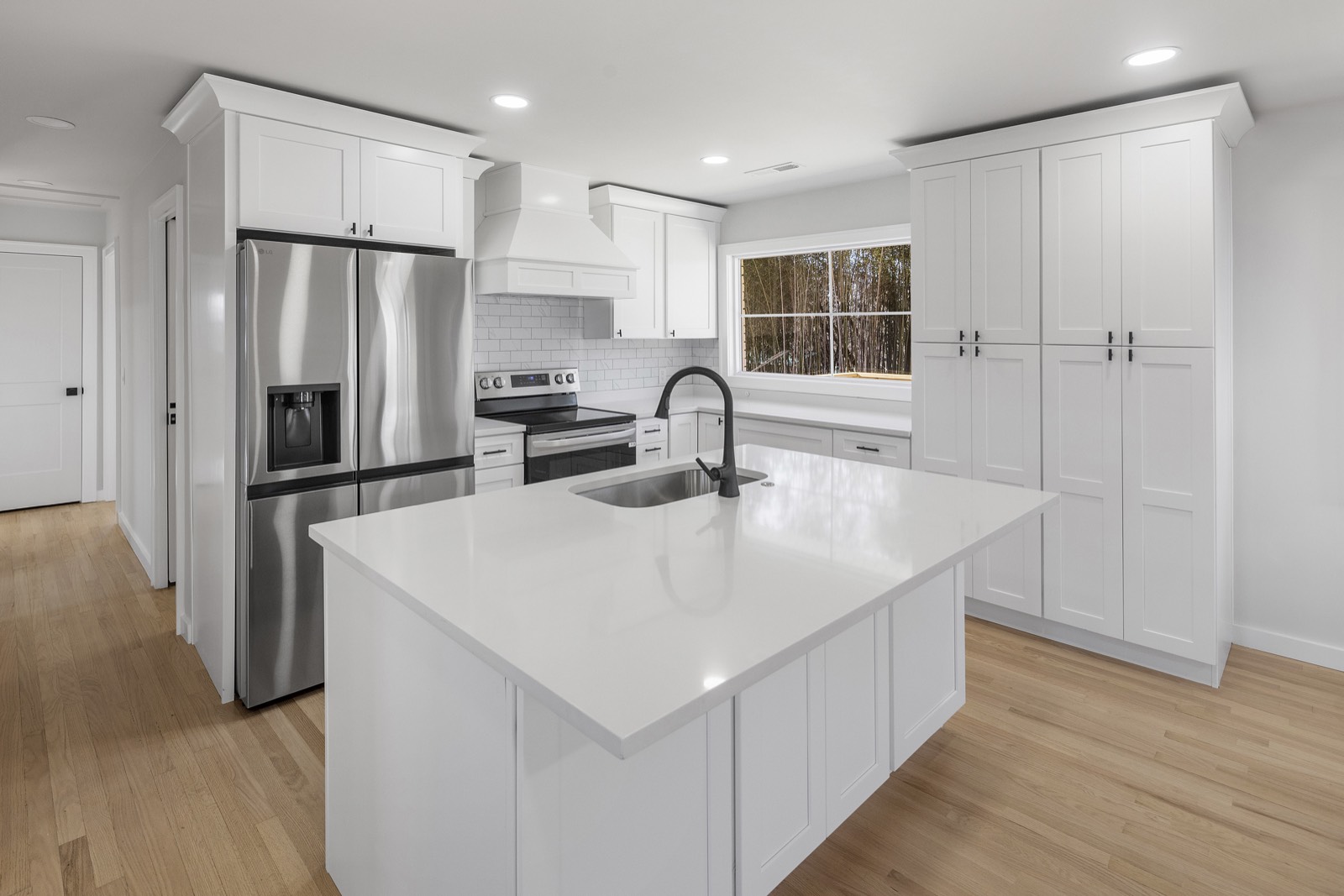 White shaker kitchen with quartz island, stainless appliances, and subway tile