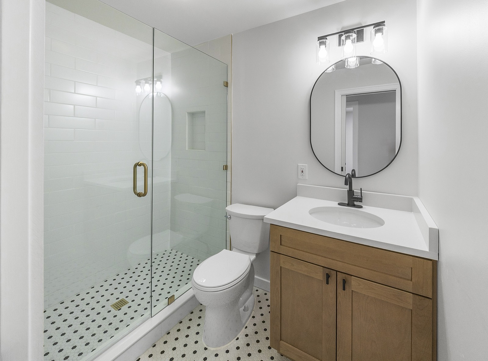 Guest bath with glass walk-in shower, wood vanity, and patterned floor tile