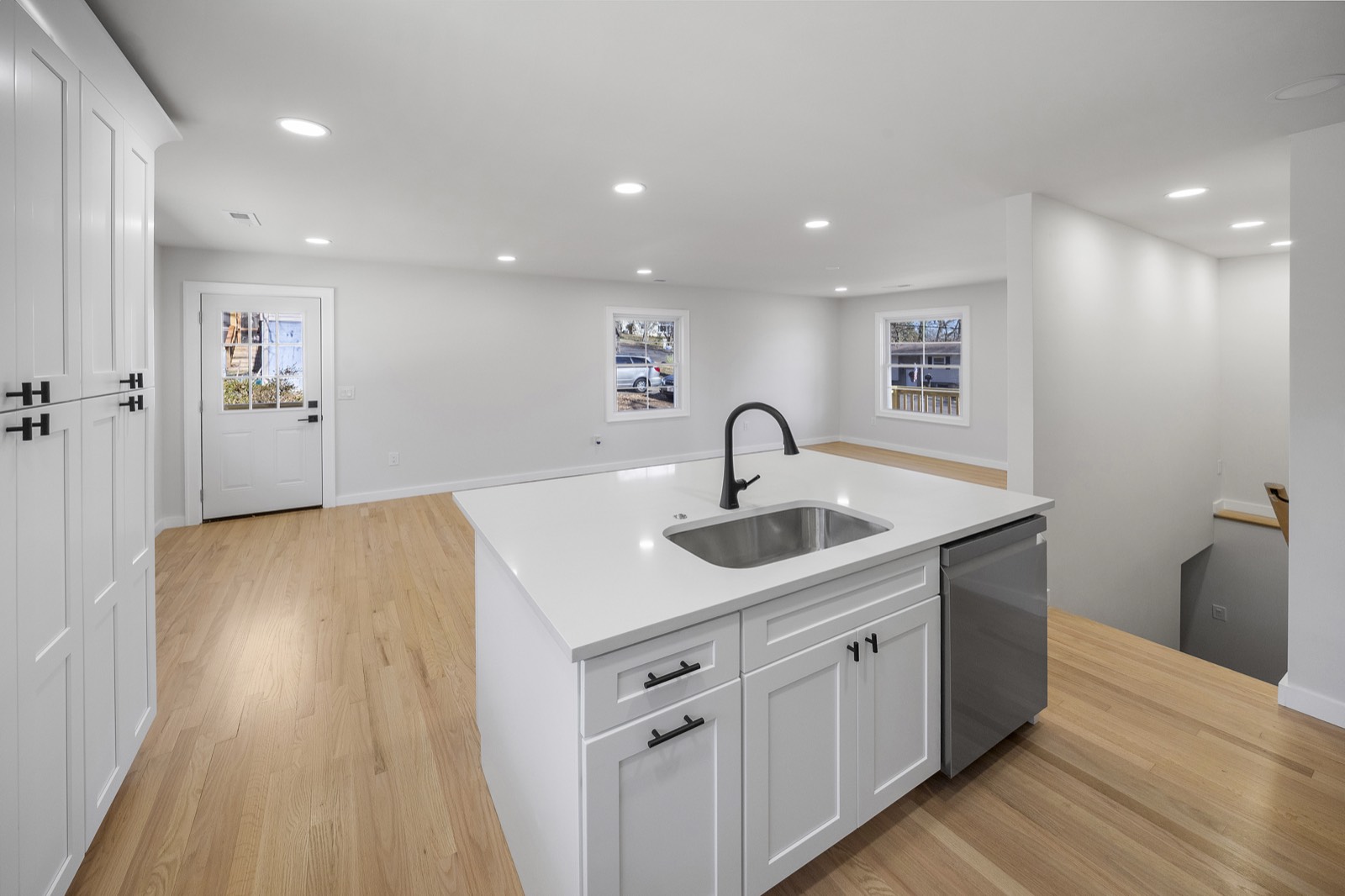 Renovated white kitchen with a quartz island, stainless appliances, and oak floors