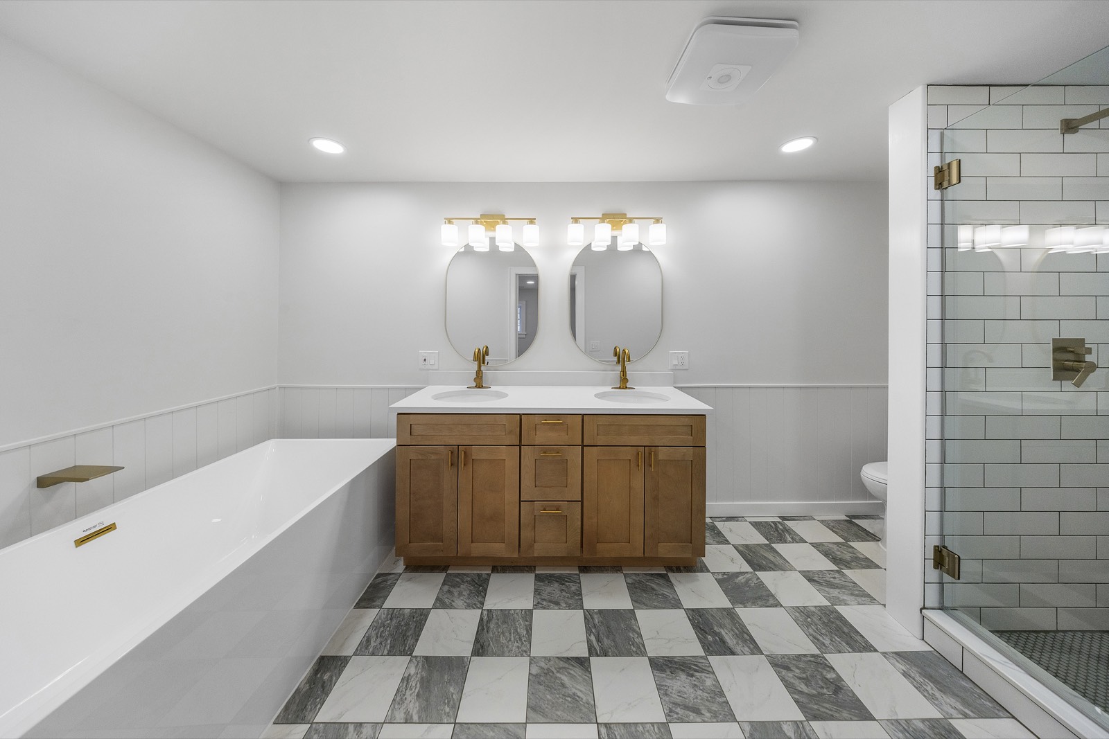 Primary bath with checkerboard marble floor, soaking tub, and double vanity