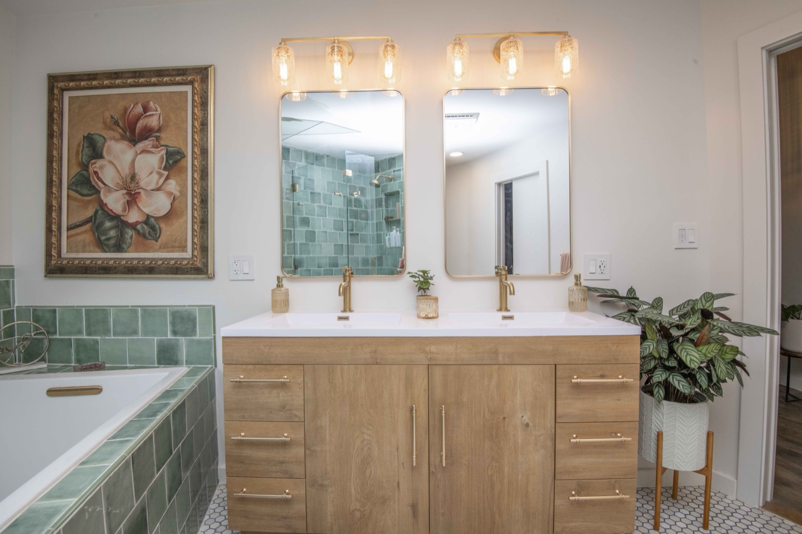 Green-tile primary bath with a soaking tub, double vanity, and botanical art