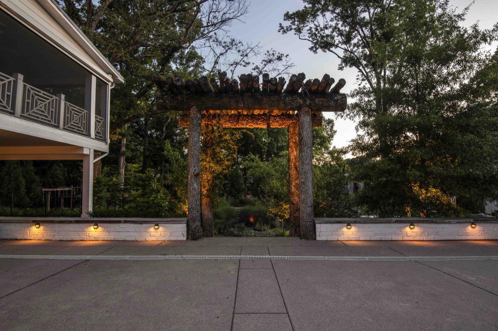 Covered porch and deck glowing under warm string lighting at dusk
