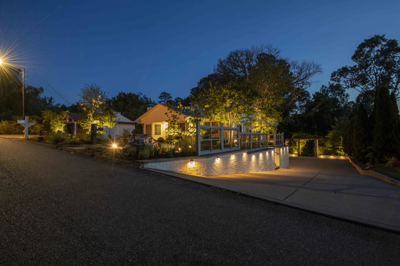Home and lit retaining-wall garden at blue hour from the street