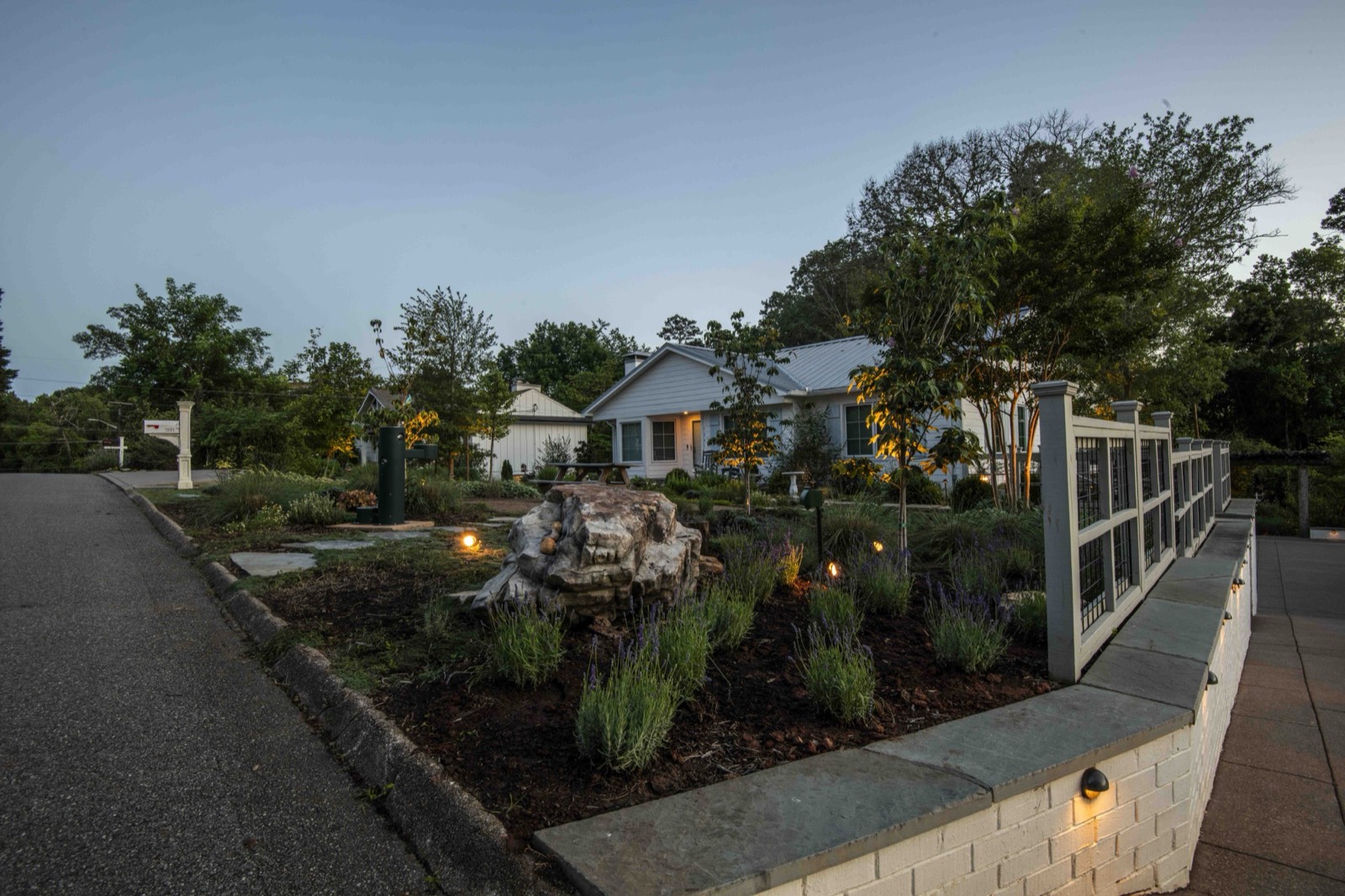 Terraced garden beds and a lit stone path glowing at sunset