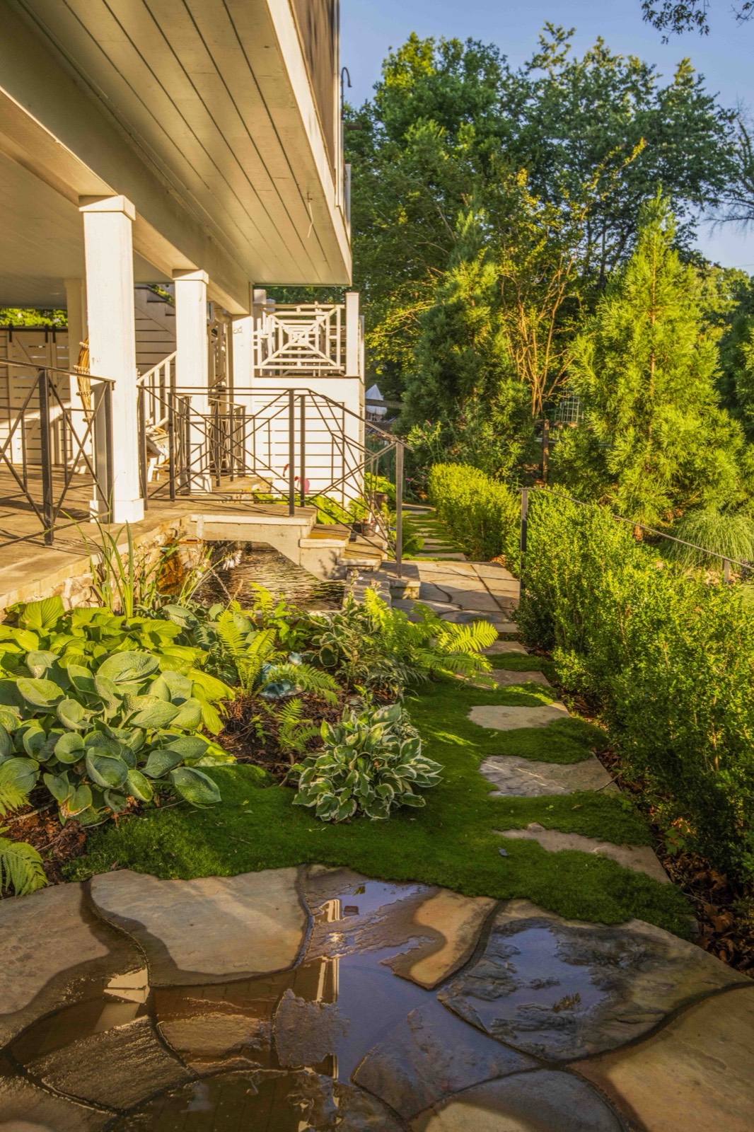 Covered side porch and walkway lined with columns and shade gardens