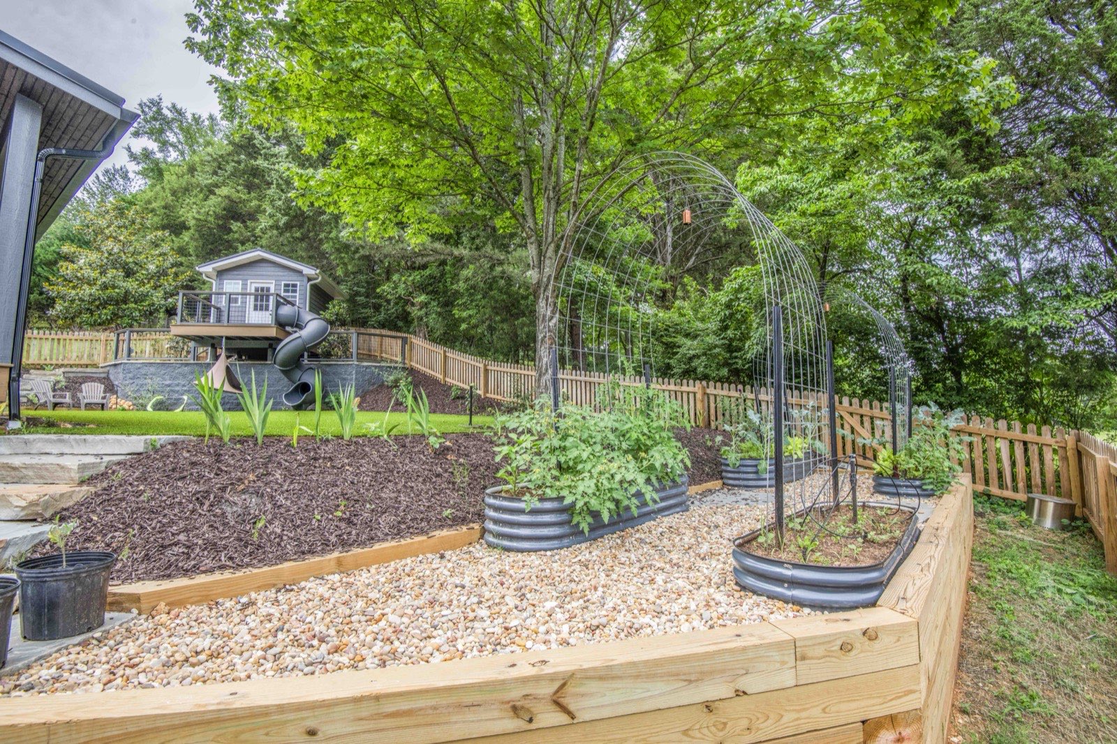 Backyard garden with raised beds, a tree swing, and mature shade trees