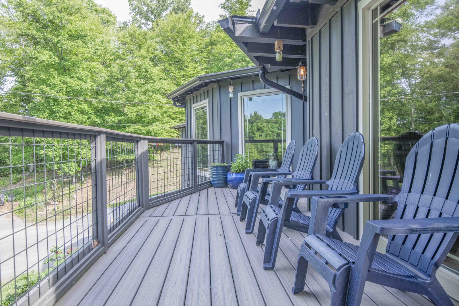 Elevated deck with hog-wire railings and a row of blue Adirondack chairs