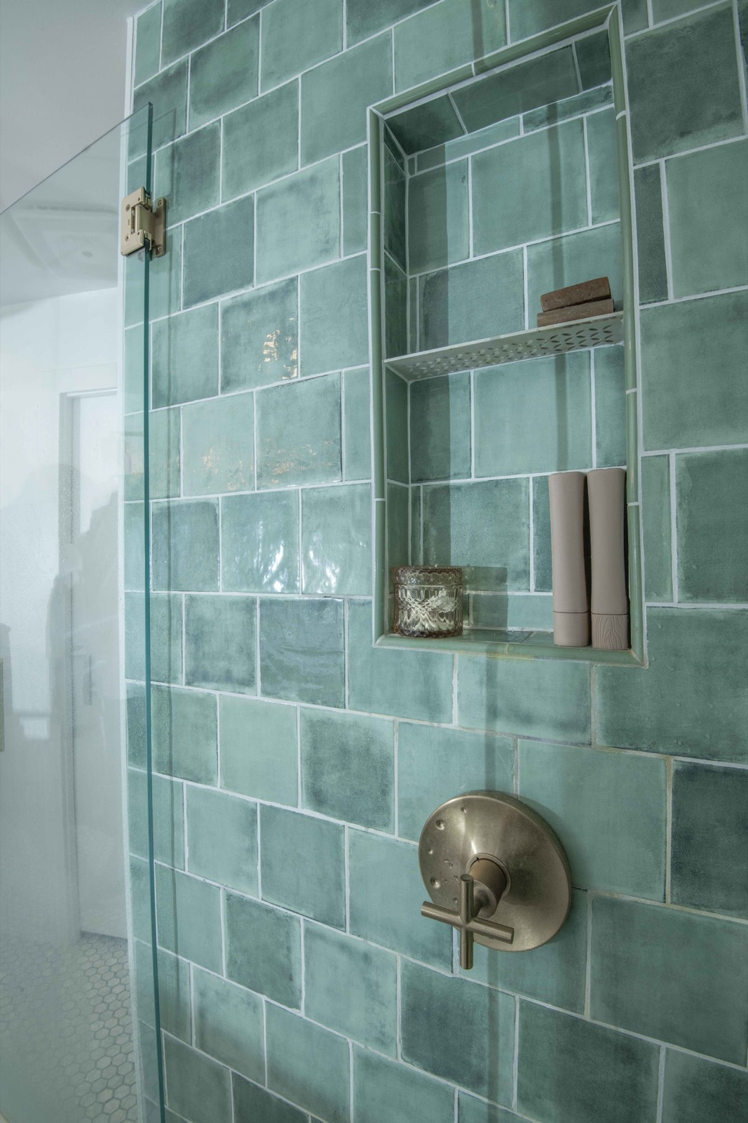 Green-tile walk-in shower with a tiled niche and brushed-nickel fixtures