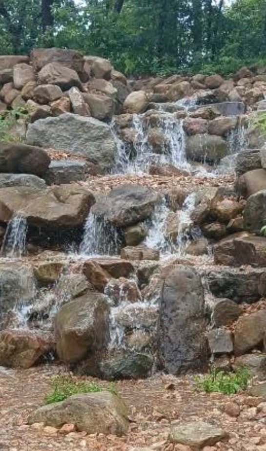 Multi-tier cascade of water running down a hillside of stacked field stone